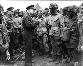 Black and white photo in which General Dwight D. Eisenhower addresses American paratroopers prior to D-Day.